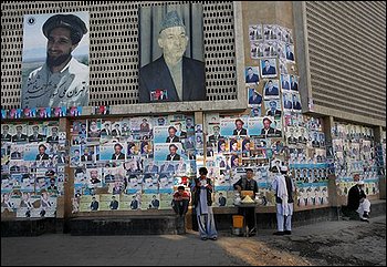 Afghans have breakfast along a wall covered with election campaign posters in downtown Kabul, Afghanistan, Wednesday, Aug. 19, 2009, on the eve of the presidential elections. (AP Photo/David Guttenfelder)